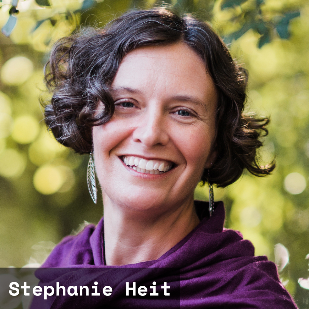 Photo credit: Tamara Wade. A headshot of Stephanie Heit, a white queer cis woman smiling, wearing a purple wrap, with brown wavy hair in a bob. She is on (perhaps in, feet dangling) the Huron River with background muted green of tree leaves, and dappled light before dusk.